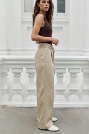 Pantalón de fit wide leg, cintura alta con pretina, trabillas y doble lazo amarrable, pinzas frontales y bolsillos delanteros. Cierre frontal con broche y cremallera ocultos.