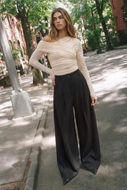 Pantalón de fit wide leg, cintura alta, pretina con detalle v posterior y trabillas, pinzas frontales, bolsillos delanteros y vivos decorativos posteriores. Cierre frontal con botón en contraste y cremallera ocultas.