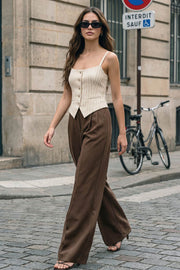 Pantalón de fit wide leg, cintura alta, pretina con detalle v posterior y trabillas, pinzas frontales, bolsillos delanteros y vivos decorativos posteriores. Cierre frontal con botón en contraste y cremallera ocultas.
