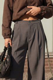 Pantalón de fit wide leg, cintura alta, pretina con detalle v posterior y trabillas, pinzas frontales, bolsillos delanteros y vivos decorativos posteriores. Cierre frontal con botón en contraste y cremallera ocultas.