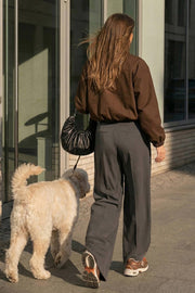 Pantalón de fit wide leg, cintura alta, pretina con detalle v posterior y trabillas, pinzas frontales, bolsillos delanteros y vivos decorativos posteriores. Cierre frontal con botón en contraste y cremallera ocultas.