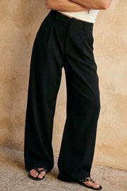 Pantalón de fit barrel, pinzas frontales, cintura media con pretina y trabillas, bolsillos delanteros y vivos decorativos posteriores. Cierre frontal con broche y cremallera ocultos.