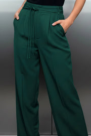 Pantalón de fit recto, pinzas con raya frontal y posterior, bolsillos delanteros, cintura alta con trabillas, doble lazo amarrable del mismo tejido y cierre frontal con cremallera oculta.