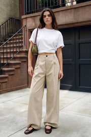 Pantalón de fit wide leg, cintura alta con pretina con detalle v posterior y trabillas, pinzas frontales, bolsillos delanteros, vivos decorativos posteriores, cierre frontal con botón en contraste y cremallera oculta.