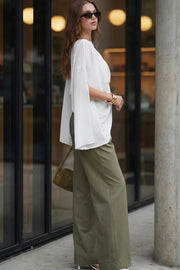 Pantalón de fit wide leg, cintura alta con pretina con detalle v posterior y trabillas, pinzas frontales, bolsillos delanteros, vivos decorativos posteriores, cierre frontal con botón en contraste y cremallera oculta.