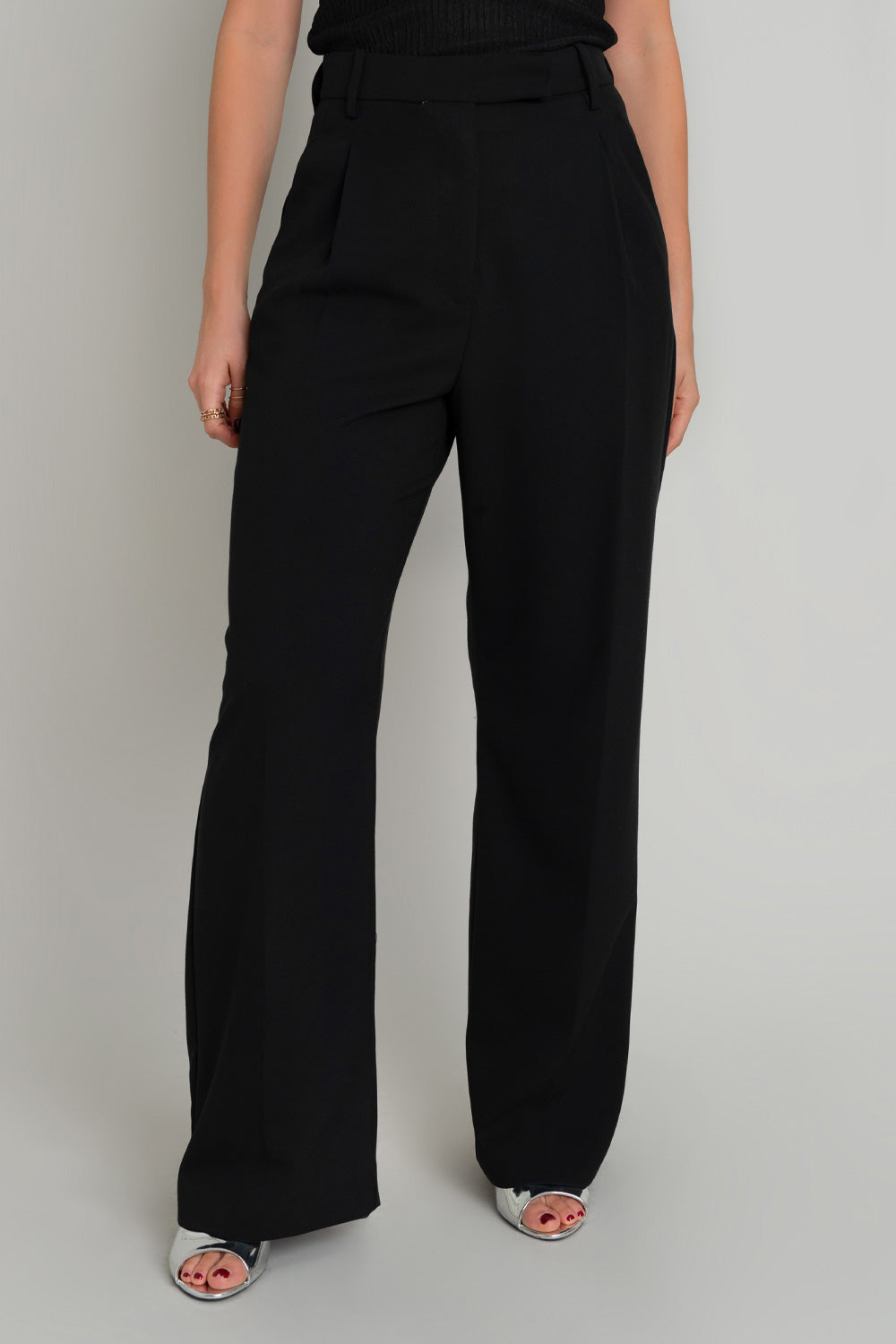 Pantalón de fit wide leg, cintura alta con pretina y trabillas, pinzas frontales con raya frontal, bolsillos delanteros, vivo decorativo posterior, cierre frontal con broche y cremallera ocultos.
