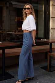 Pantalón de fit wide leg, cintura alta con pretina y trabillas, pinzas frontales con raya frontal, bolsillos delanteros, vivo decorativo posterior, cierre frontal con broche y cremallera ocultos.