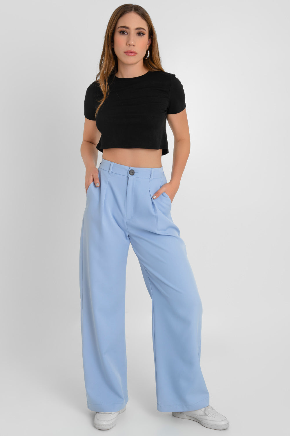 Pantalón fluido de fit wide leg, cintura alta con pretina elástica posterior, trabillas, bolsillos delanteros, pinzas frontales, cierre frontal con cremallera oculta y botón en contraste.