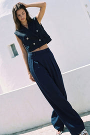 Pantalón de fit wide leg, cintura alta con pretina, trabillas, pinzas frontales y bolsillos delanteros. Cierre frontal con broche y cremallera ocultos.