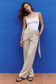 Pantalón fluido de fit recto, cintura media con pretina elástica, bolsillos delanteros y detalle de pareo decorativo con nudo lateral.