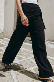 Pantalón fluido de fit recto, cintura media con pretina elástica, bolsillos delanteros y detalle de pareo decorativo con nudo lateral.