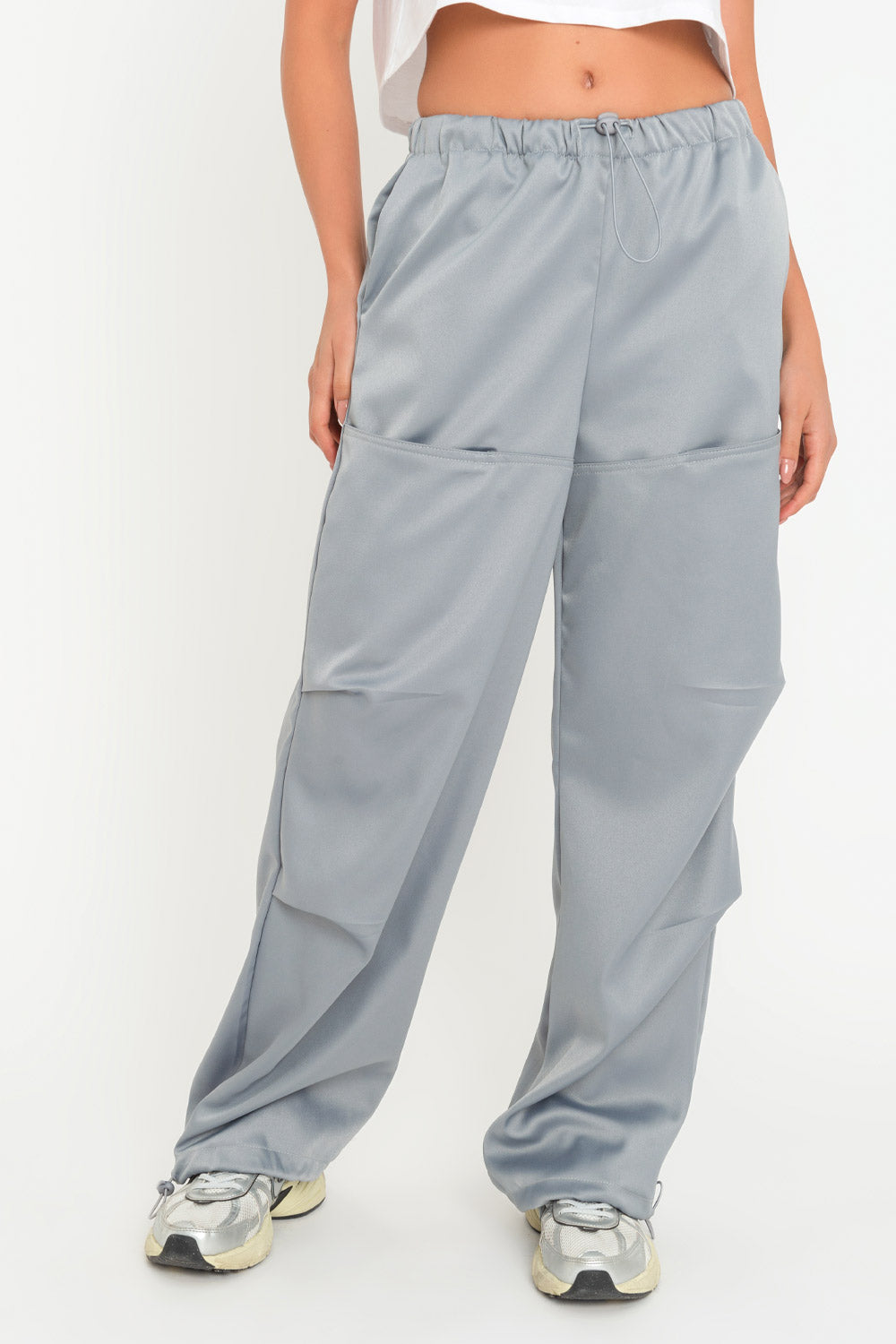 Pantalón parachute satinado de cintura alta con pretina elástica y jareta ajustable, de pierna amplia, plisados decorativos frontales, detalle de bajo con jaretas elásticas ajustables.