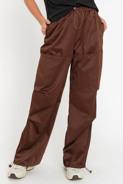 Pantalón parachute satinado de cintura alta con pretina elástica y jareta ajustable, de pierna amplia, plisados decorativos frontales, detalle de bajo con jaretas elásticas ajustables.