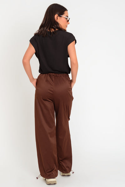 Pantalón parachute satinado de cintura alta con pretina elástica y jareta ajustable, de pierna amplia, plisados decorativos frontales, detalle de bajo con jaretas elásticas ajustables.