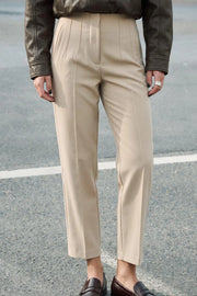 Pantalón de fit recto, cintura alta con pinzas, vivos decorativos frontales, detalle posterior en v, raya frontal y posterior. Cierre frontal con cremallera oculta.