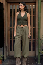Pantalón de fit wide leg, cintura alta con pretina, trabillas y lazo amarrable en cintura, pinzas frontales y bolsillos delanteros. Cierre frontal con broche y cremallera oculta.