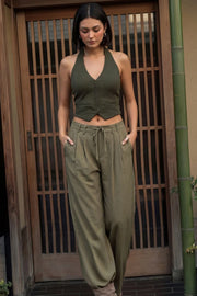Pantalón de fit wide leg, cintura alta con pretina, trabillas y lazo amarrable en cintura, pinzas frontales y bolsillos delanteros. Cierre frontal con broche y cremallera oculta.