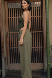 Pantalón de fit wide leg, cintura alta con pretina, trabillas y lazo amarrable en cintura, pinzas frontales y bolsillos delanteros. Cierre frontal con broche y cremallera oculta.