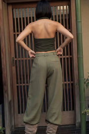Pantalón de fit wide leg, cintura alta con pretina, trabillas y lazo amarrable en cintura, pinzas frontales y bolsillos delanteros. Cierre frontal con broche y cremallera oculta.