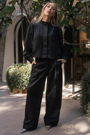Pantalón de fit wide leg, cintura alta con pretina y trabillas, bolsillos decorativos delanteros, cierre frontal con botón y cremallera oculta.
