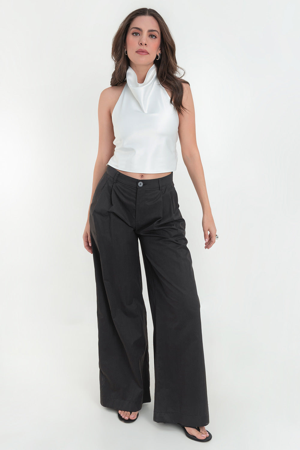 Pantalón de fit wide leg, cintura alta con pretina y trabillas, pinzas frontales, bolsillos delanteros, cierre frontal con botón y cremallera oculta.