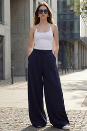 Pantalón de fit wide leg, cintura alta con pretina, pinzas frontales, bolsillos delanteros y vivos decorativos posteriores. Cierre frontal con broche y cremallera ocultos. Detalle v en pretina posterior.