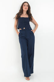 Pantalón de fit wide leg, cintura media con pretina y trabillas, pinzas frontales, vivo decorativo posterior, bolsillos delanteros, raya frontal y posterior. Cierre frontal con botón y cremallera oculta.