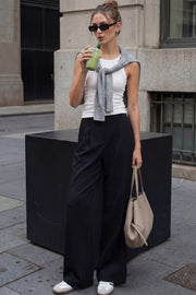 Pantalón de fit wide leg, cintura alta con pretina elástica posterior, trabillas, pinzas frontales y bolsillos delanteros.