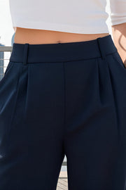 Pantalón de fit wide leg, cintura alta con pretina elástica posterior, trabillas, pinzas frontales y bolsillos delanteros.