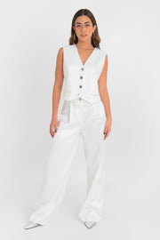 Pantalón satinado de fit wide leg con pinzas frontales, cintura alta con pretina y trabillas, bolsillos delanteros, cierre frontal con botón en contraste y cremallera oculta.