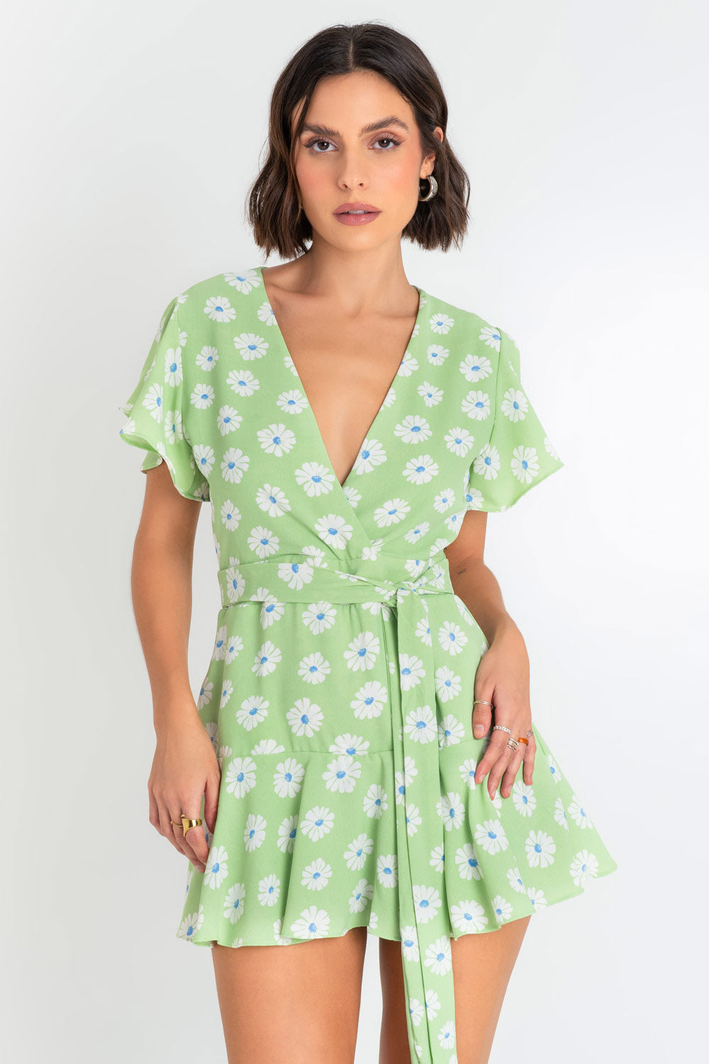 Playsuit de fit ajustado, estampado floral, manga corta con olanes, escote v cruzado, pretina con lazo frontal amarrable y bajo con olanes en borde. Cierre posterior con cremallera oculta.