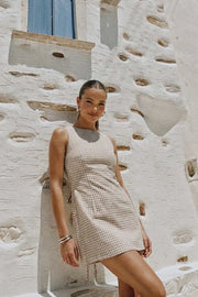 Playsuit de estampado cuadros, fit ajustado, cuello barco, sin mangas, pinzas frontales, lazo amarrable posterior y cierre con cremallera oculta.