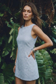 Playsuit de estampado cuadros, fit ajustado, cuello barco, sin mangas, pinzas frontales, lazo amarrable posterior y cierre con cremallera oculta.