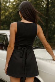 Playsuit de fit ajustado, cuello barco, sin mangas, pinzas frontales, lazo amarrable posterior y cierre con cremallera oculta.