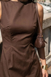 Playsuit de fit ajustado, cuello barco, sin mangas, pinzas frontales, lazo amarrable posterior y cierre con cremallera oculta.