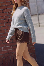 Short corto satinado de fit fluido, cintura media con pretina elástica y detalle de encaje decorativo en bajo.