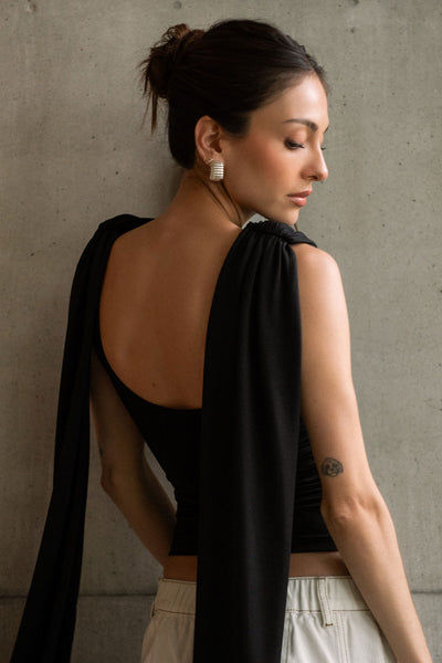 Top de fit ajustado, sin mangas, cuello redondo y detalle decorativo frontal con plisados en hombros.