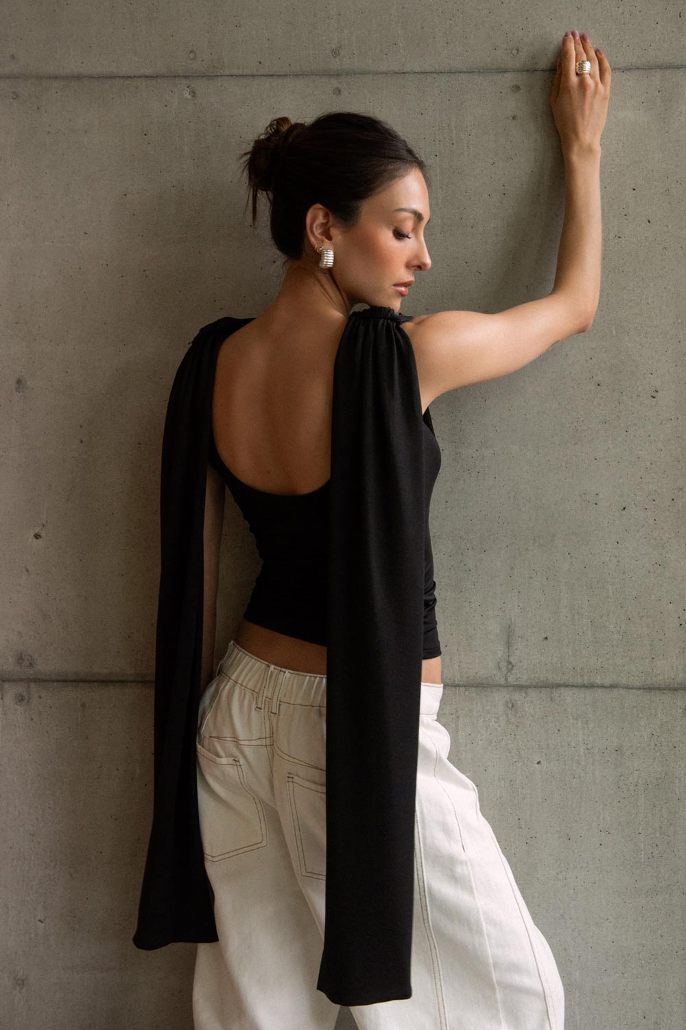 Top de fit ajustado, sin mangas, cuello redondo y detalle decorativo frontal con plisados en hombros.