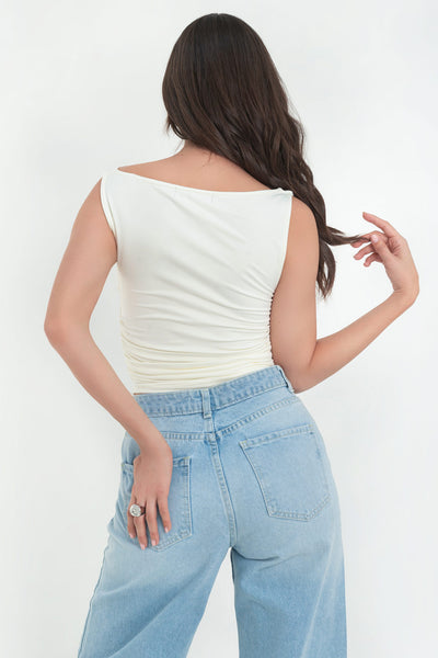 Top corto de fit ajustado, sin mangas, cuello barco con escote fluido, plisados en costados y bajo curveado.