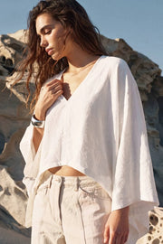 Blusa tipo capa de fit fluido, manga larga amplia, cuello v y bajo asimétrico. Detalle de textura en tejido.