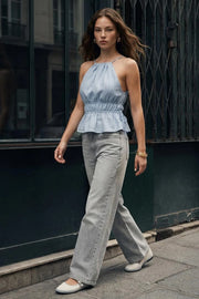 Top corto de cuello halter con plisados, estampado rayas, tirantes delgados, detalle de rib con plisados y lazos laterales en costados, peplum con olanes en bajo y cierre posterior con botón y ojal.