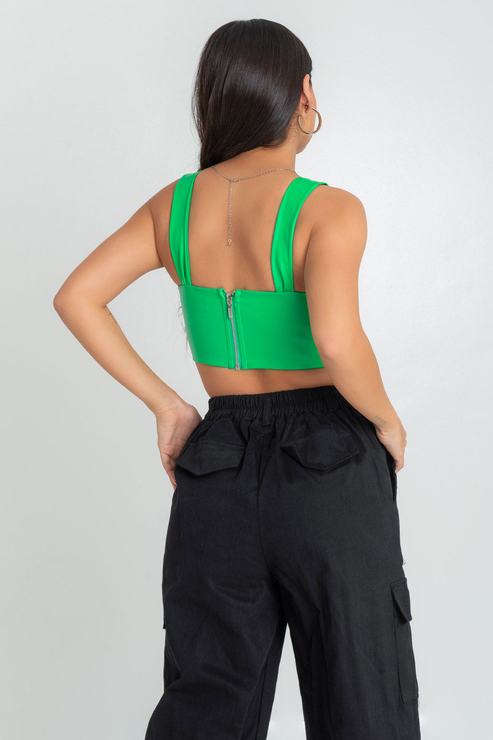 Top corset de fit ajustado, efecto piel, escote redondeado con detalles plisados, costuras frontales con varillas, tirantes y detalle de bajo curveado con cut outs laterales. Cierre posterior cremallera visible en contraste.