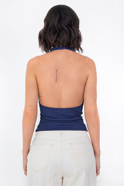 Top corto ajustado de cuello halter con escote fluido, sin mangas, escote en espalda, cierre posterior con botón y ojal.
