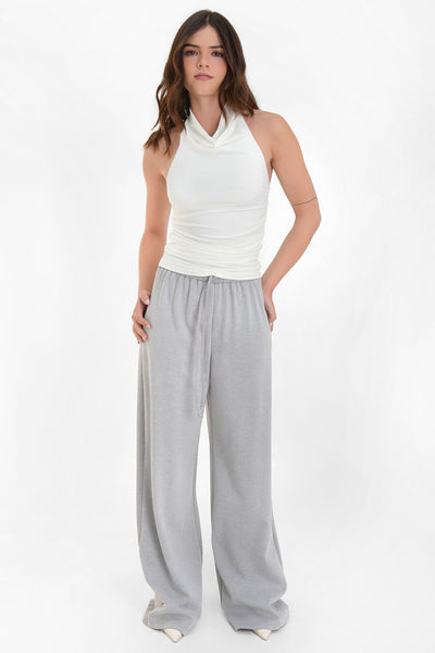 Top corto sin mangas, de fit ajustado, detalles plisados en costados, cuello halter fluido y escote en espalda.