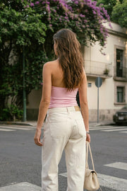 Top halter corto de fit ajustado, sin mangas, cuello halter fluido con plisados y escote en espalda. Detalle de bajo diagonal asimétrico.