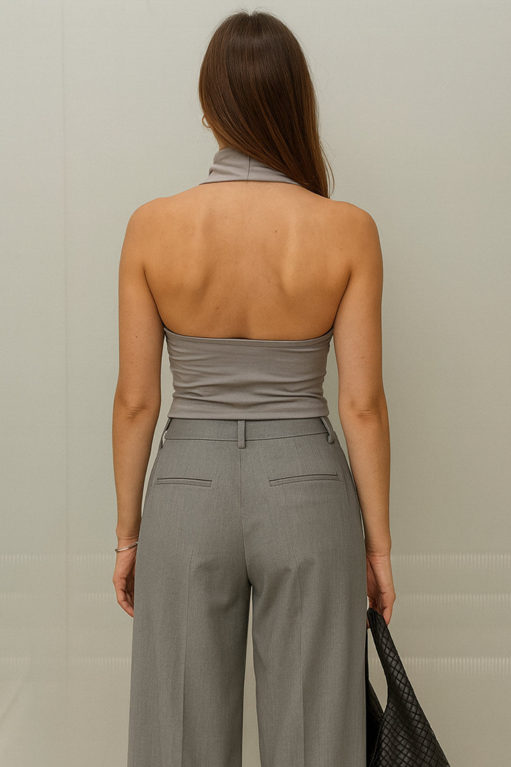 Top halter corto de fit ajustado, sin mangas, cuello halter fluido con plisados y escote en espalda. Detalle de bajo diagonal asimétrico.