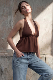 Top canalé de cuello halter con nudo amarrable posterior, escote v con plisados frontales, rib elástico en cintura y peplum olanes. Detalle de escote en espalda con lazo amarrable posterior.