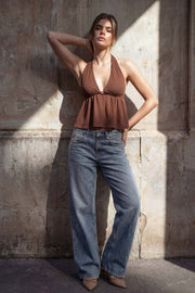 Top canalé de cuello halter con nudo amarrable posterior, escote v con plisados frontales, rib elástico en cintura y peplum olanes. Detalle de escote en espalda con lazo amarrable posterior.