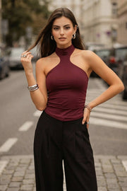 Top halter de fit ajustado, sin mangas, cuello alto, escote en espalda, cierre posterior con botón y ojal.