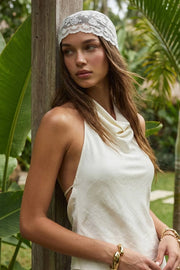 Top de cuello halter fluido, escote en espalda con lazo amarrable posterior, cierre con botón y ojal.